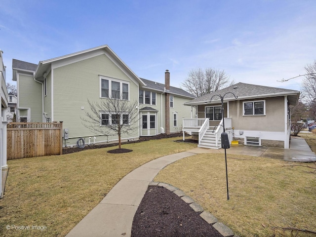 rear view of house featuring cooling unit, fence, roof with shingles, a patio area, and a lawn