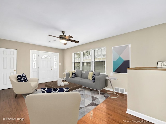 living room with baseboards, wood finished floors, visible vents, and ceiling fan