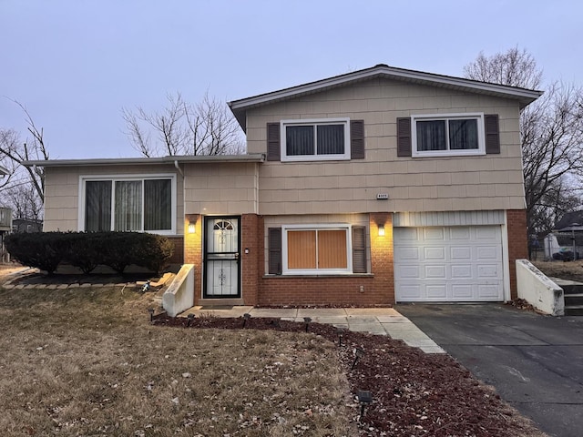 tri-level home featuring a garage, brick siding, and driveway