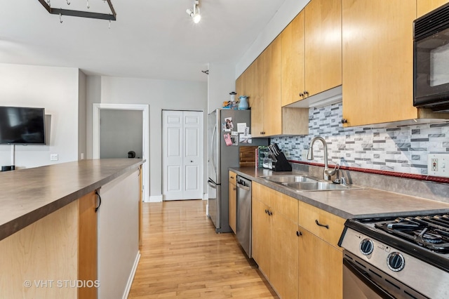 kitchen featuring dark countertops, decorative backsplash, stainless steel appliances, and a sink