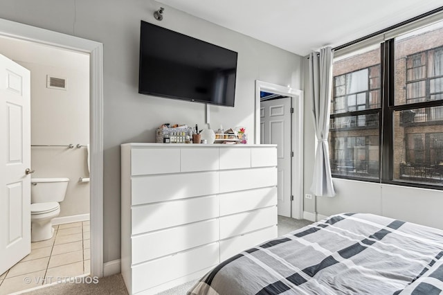 bedroom featuring visible vents, baseboards, ensuite bath, and light tile patterned flooring