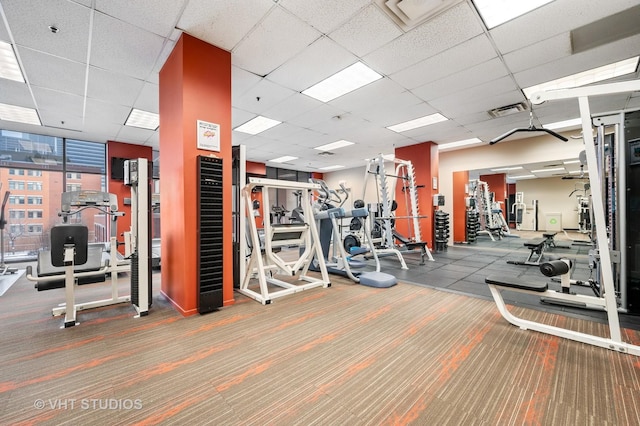 exercise room with visible vents, a paneled ceiling, and carpet