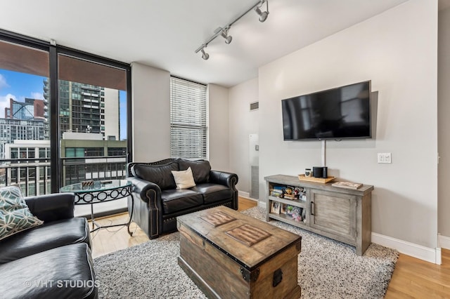 living room with visible vents, rail lighting, baseboards, and wood finished floors