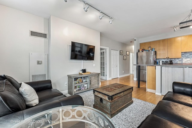 living room with light wood-style flooring, baseboards, and visible vents