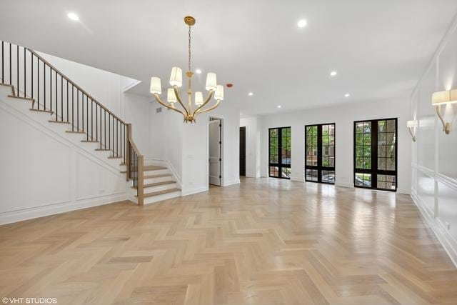 unfurnished room with a decorative wall, recessed lighting, stairs, and an inviting chandelier