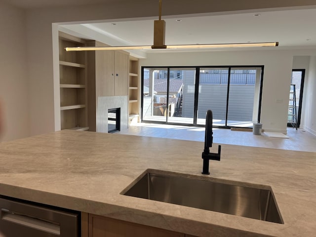 kitchen featuring a glass covered fireplace, built in features, open shelves, and a sink