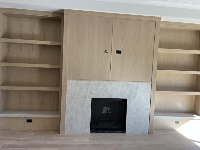 room details featuring built in features, a fireplace, and wood finished floors