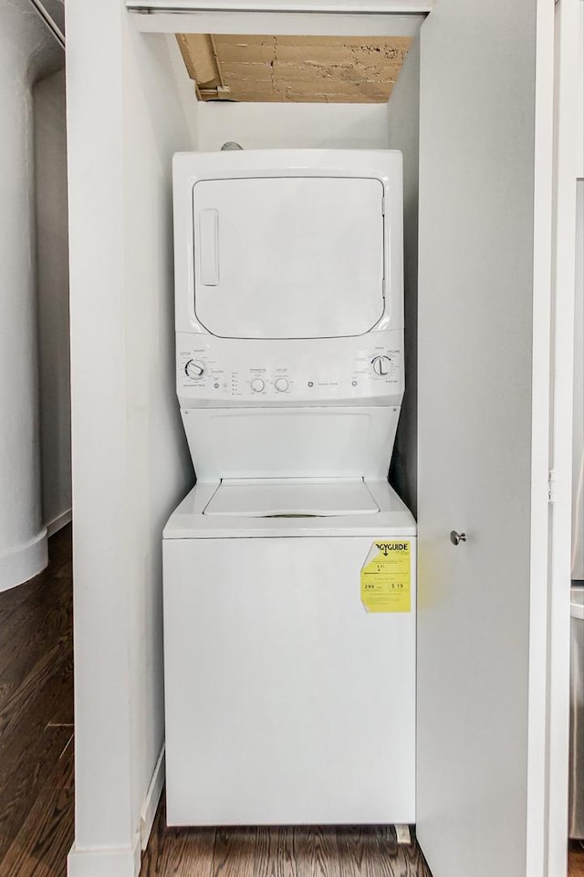 clothes washing area with laundry area, stacked washer / dryer, and wood finished floors