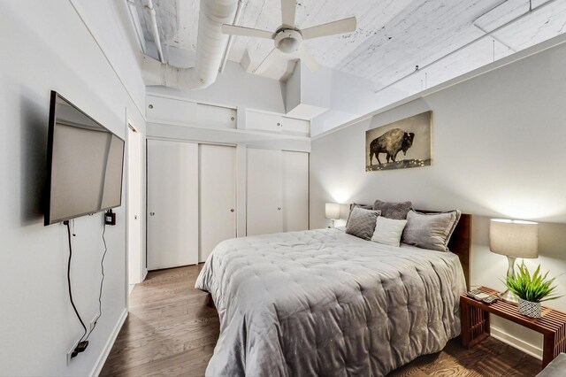 bedroom with baseboards, a ceiling fan, multiple closets, and wood finished floors