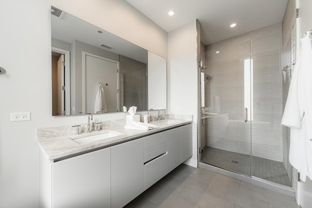 full bath with a shower stall, double vanity, visible vents, and a sink