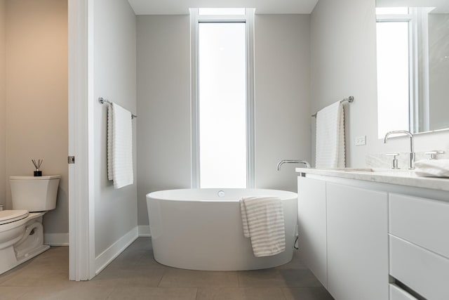 bathroom featuring tile patterned flooring, a freestanding bath, toilet, and vanity