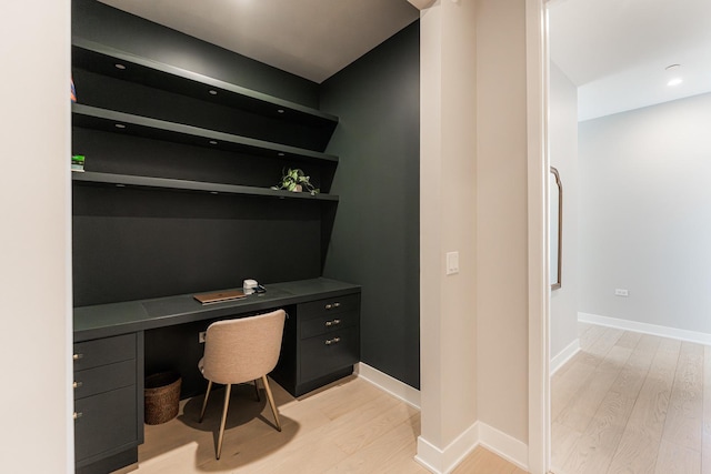 office featuring baseboards, built in desk, and light wood finished floors