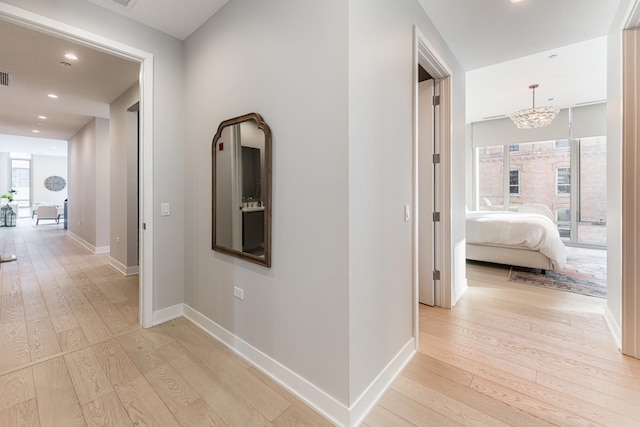 hallway featuring recessed lighting, visible vents, baseboards, and light wood finished floors