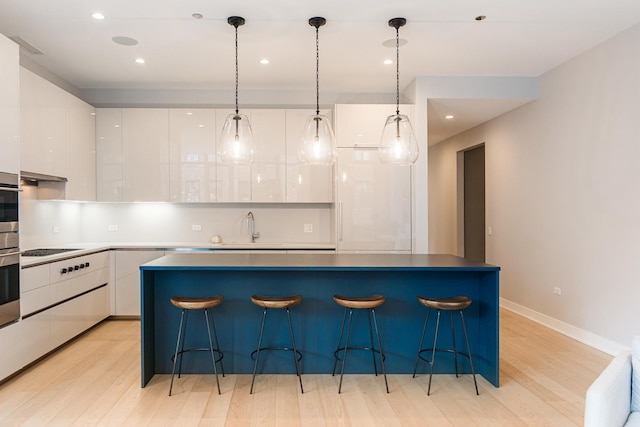 kitchen with white cabinets, modern cabinets, light wood-type flooring, and a sink