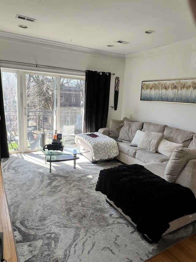 living room with visible vents, crown molding, and wood finished floors