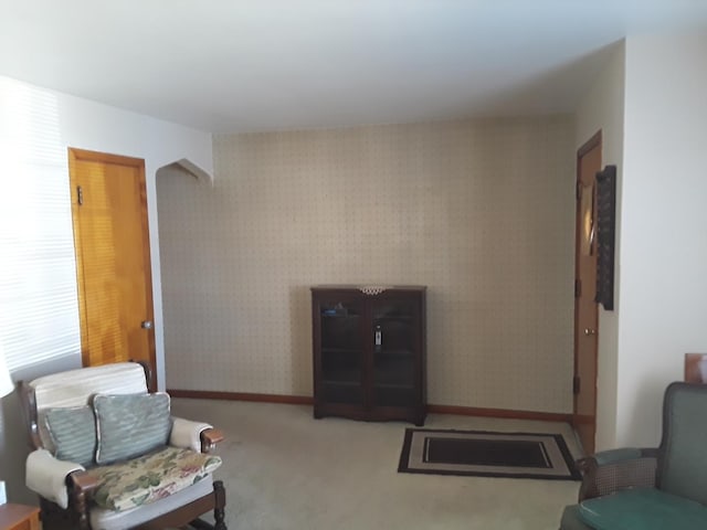 carpeted living area featuring wallpapered walls and baseboards