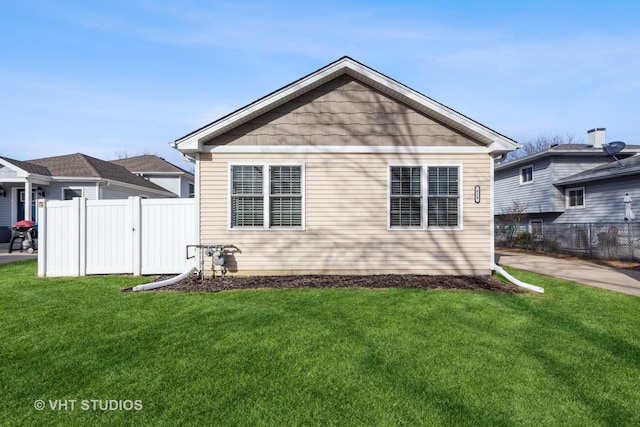 rear view of house with a lawn and fence