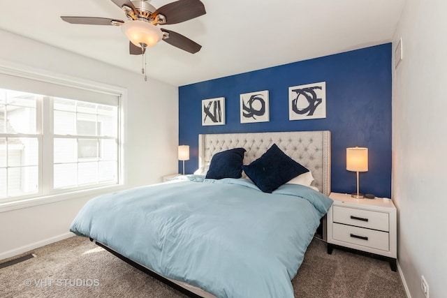 bedroom featuring an accent wall, a ceiling fan, baseboards, and carpet floors