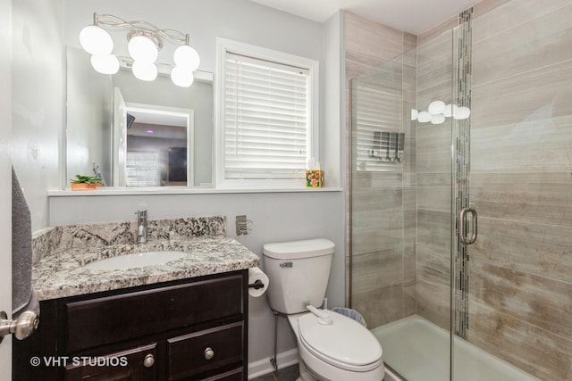 bathroom featuring a shower stall, toilet, and vanity