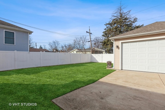 view of yard featuring concrete driveway, a fenced backyard, and a garage