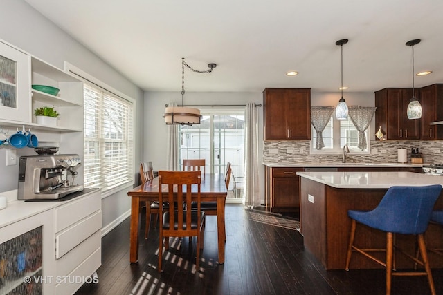 kitchen with decorative backsplash, a healthy amount of sunlight, dark wood-style floors, and light countertops