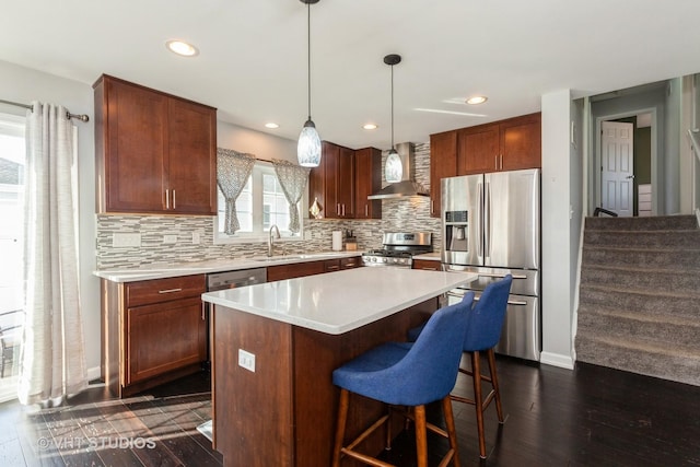 kitchen with a sink, tasteful backsplash, appliances with stainless steel finishes, and wall chimney range hood