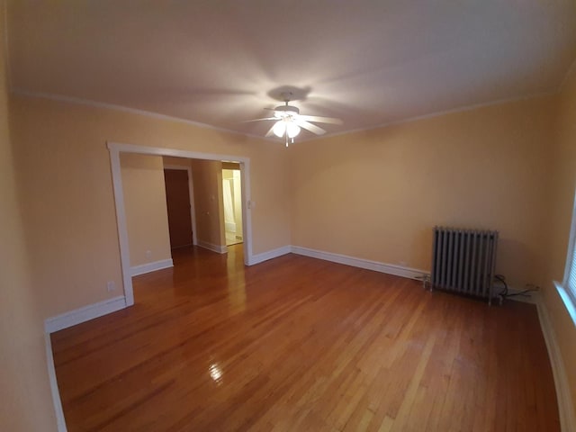 unfurnished room with radiator, wood finished floors, baseboards, ceiling fan, and ornamental molding