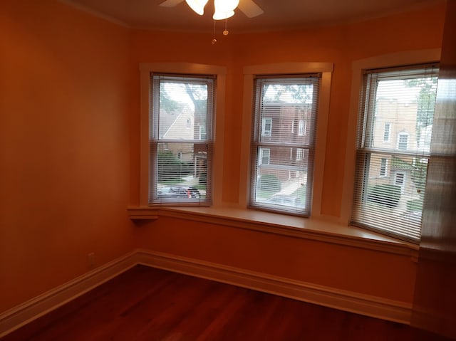 empty room featuring ornamental molding, a ceiling fan, baseboards, and wood finished floors