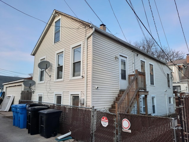 back of house with a fenced front yard, a chimney, and a garage