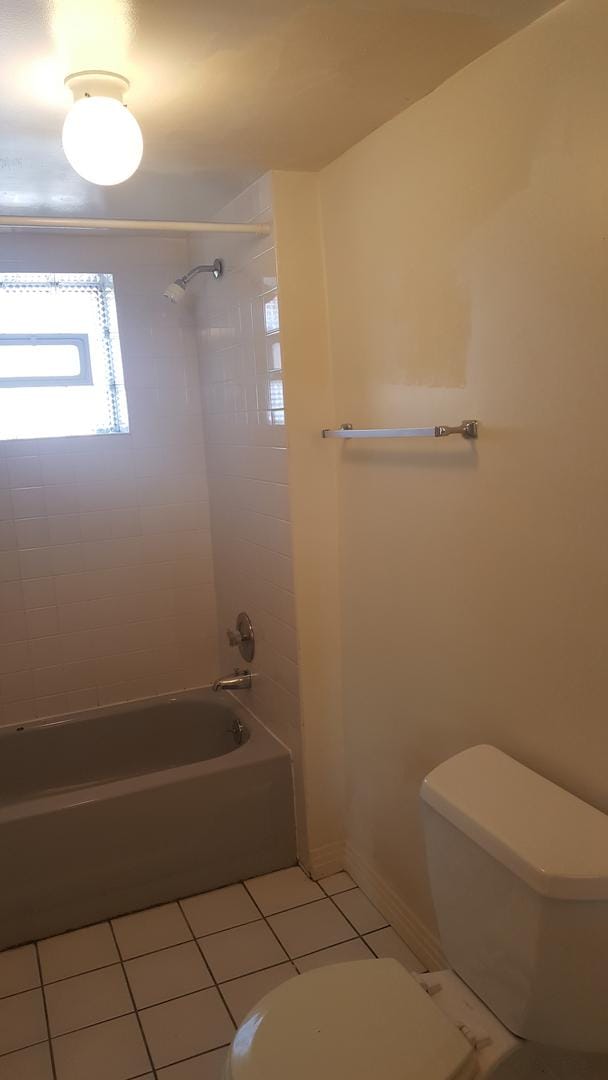 full bathroom with tile patterned floors, toilet, tub / shower combination, and baseboards