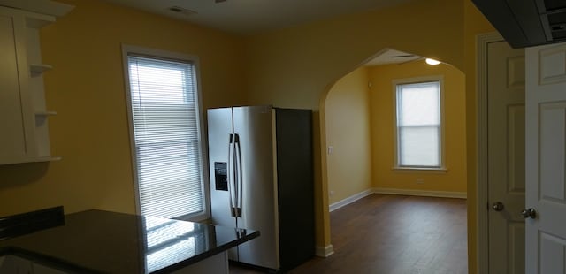 kitchen with visible vents, dark countertops, stainless steel fridge, arched walkways, and baseboards