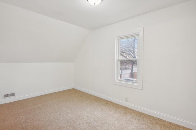 bonus room with visible vents, light carpet, lofted ceiling, and baseboards