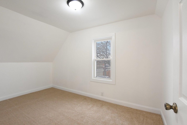 additional living space featuring baseboards, light carpet, and lofted ceiling