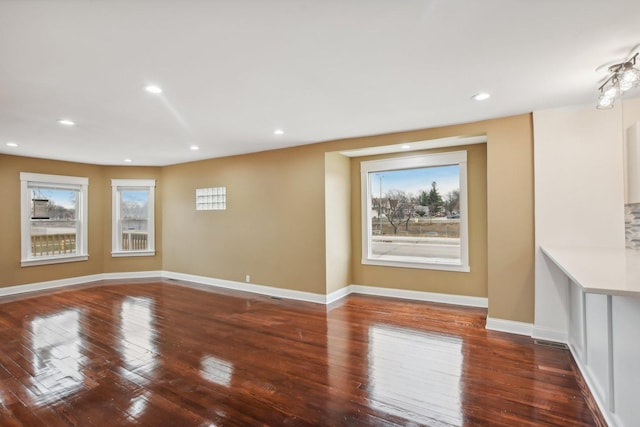 unfurnished living room with recessed lighting, baseboards, and wood-type flooring