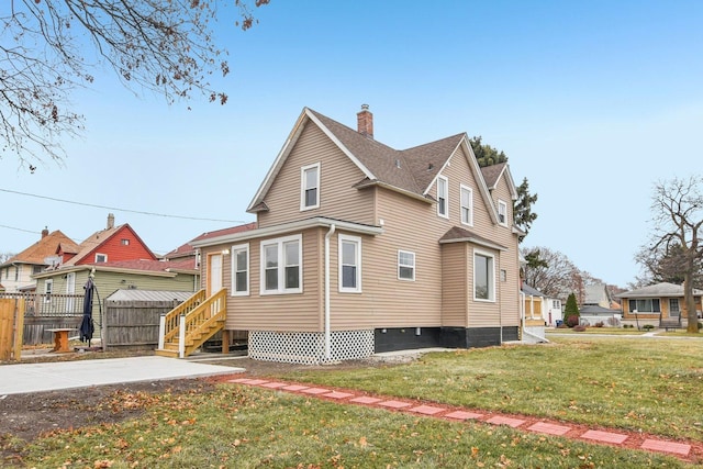 view of side of home featuring entry steps, fence, a lawn, and a chimney