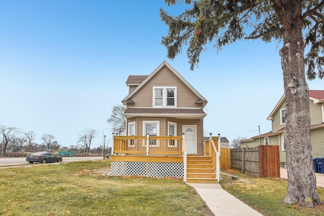 view of front of home featuring roof with shingles, a front lawn, and fence