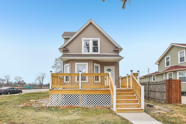 view of front of home featuring roof with shingles, a deck, and fence