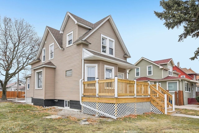 view of front of property with a wooden deck, a front yard, and a shingled roof