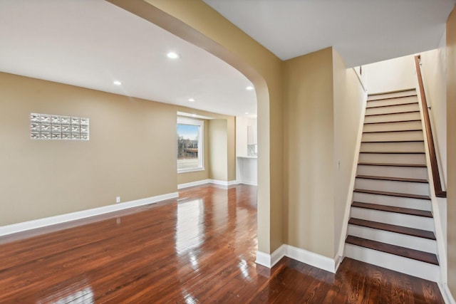 stairs with hardwood / wood-style flooring, recessed lighting, baseboards, and arched walkways