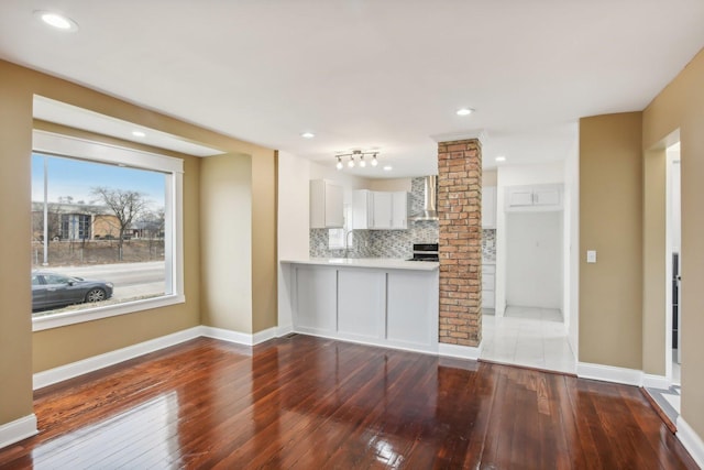 kitchen featuring stainless steel stove, white cabinets, light countertops, wood-type flooring, and tasteful backsplash