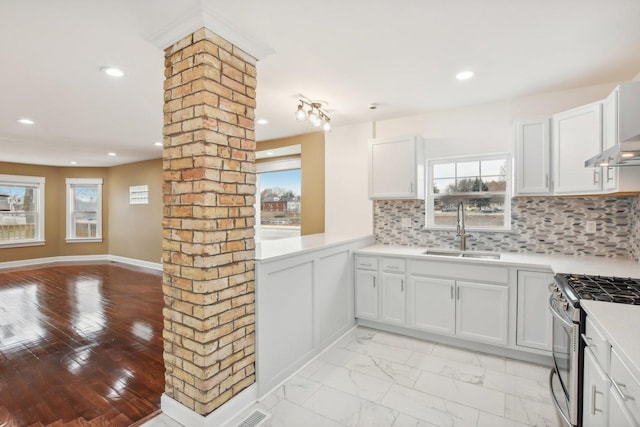 kitchen featuring gas stove, a sink, light countertops, marble finish floor, and tasteful backsplash