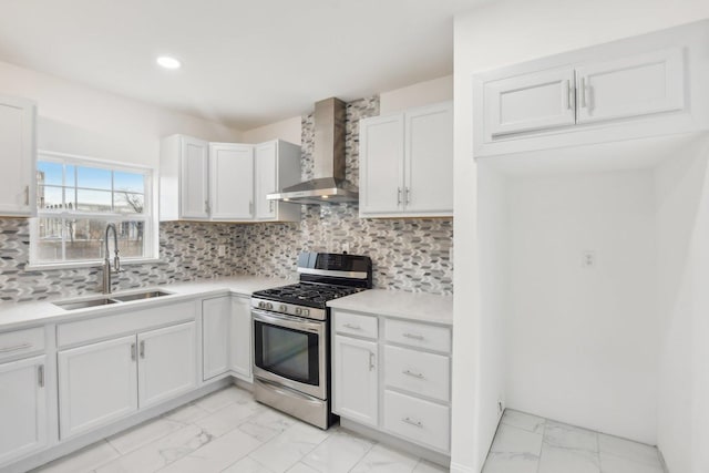 kitchen with stainless steel gas stove, marble finish floor, a sink, tasteful backsplash, and wall chimney exhaust hood