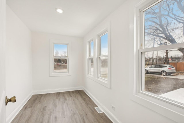 spare room featuring visible vents, baseboards, and wood finished floors