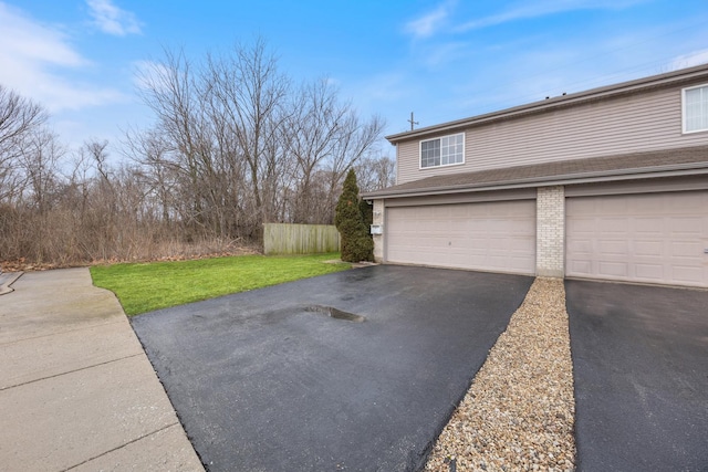 garage featuring aphalt driveway and fence