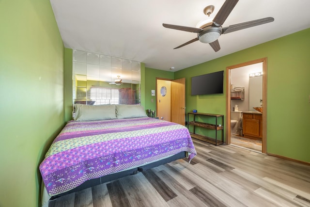 bedroom featuring ceiling fan, baseboards, light wood-style floors, and ensuite bath