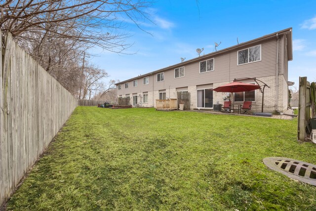 back of house with a patio, a fenced backyard, a yard, brick siding, and central AC unit