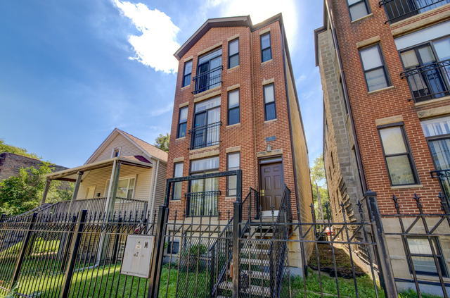 multi unit property with brick siding and a fenced front yard