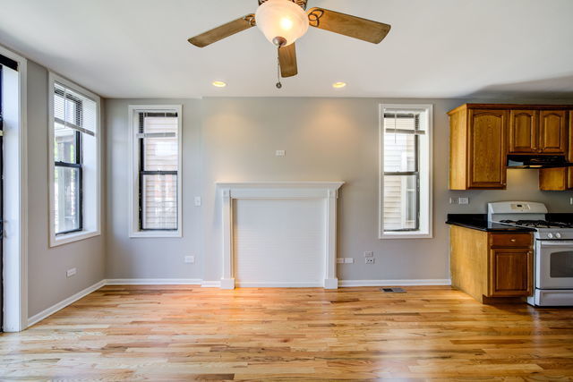 kitchen with white gas range, dark countertops, light wood finished floors, and brown cabinetry