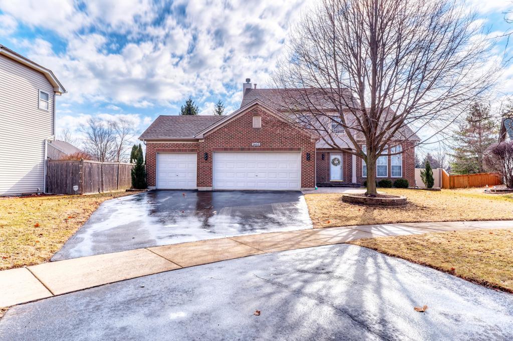 view of front facade featuring fence, driveway, a chimney, a garage, and brick siding