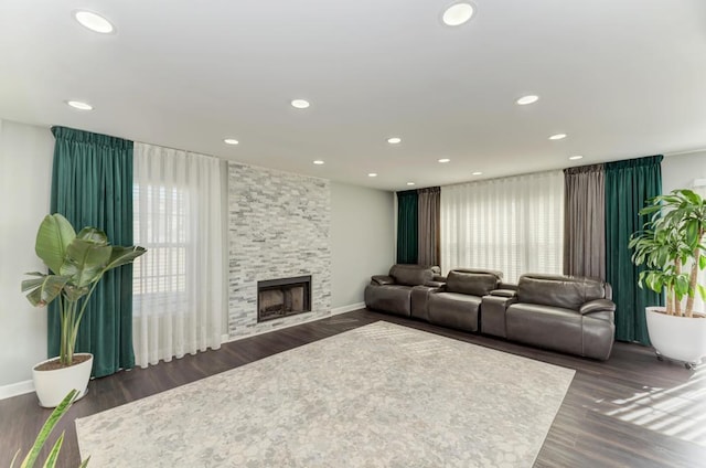 living area featuring recessed lighting, baseboards, a stone fireplace, and wood finished floors